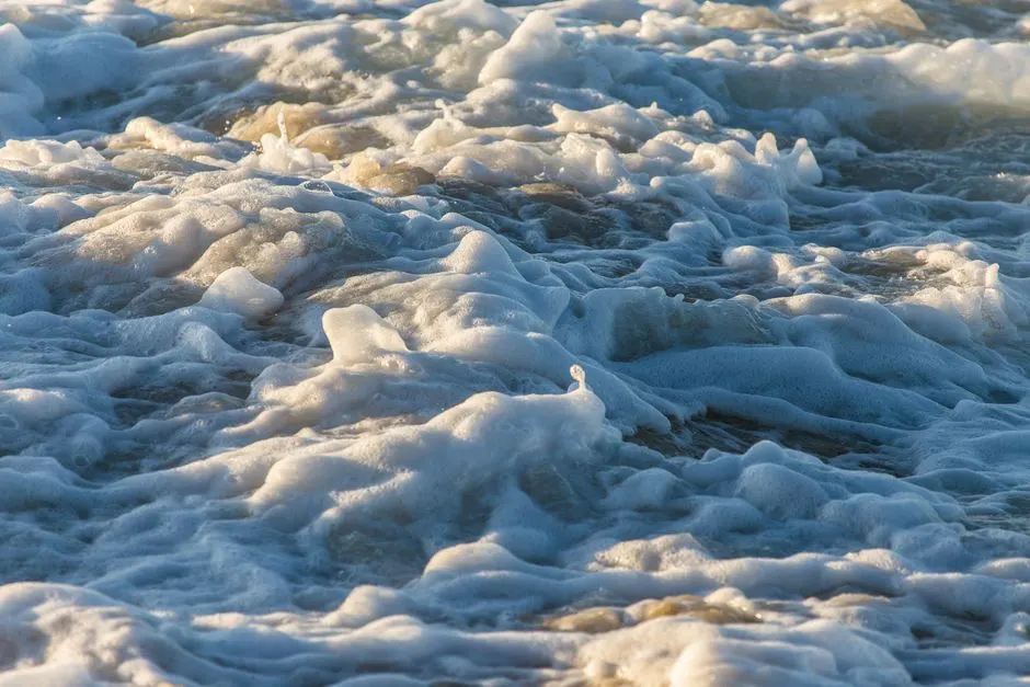 Close-up view of ocean waves with sea foam creating dynamic textures and motion.